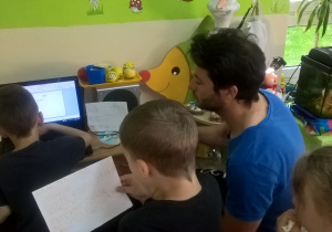 Zdjęcie przedstawia działania dzieci z wolontariuszem, naukę języka hiszpańskiego. Wszyscy są zgromadzeni są przed komputerem.